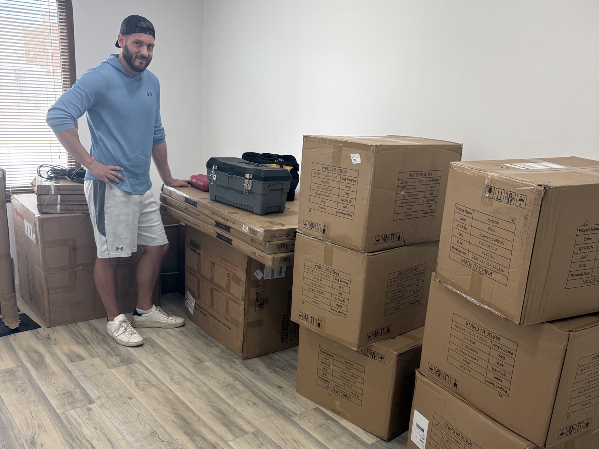 Setting up a new space: a man stands beside a workbench and stacks of furniture boxes waiting to be unpacked.